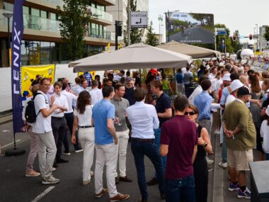 Spectators along the route with race livestream in the background