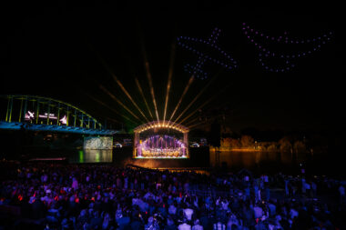Stage on the water with two LED screens on the left and right sides of the stage.